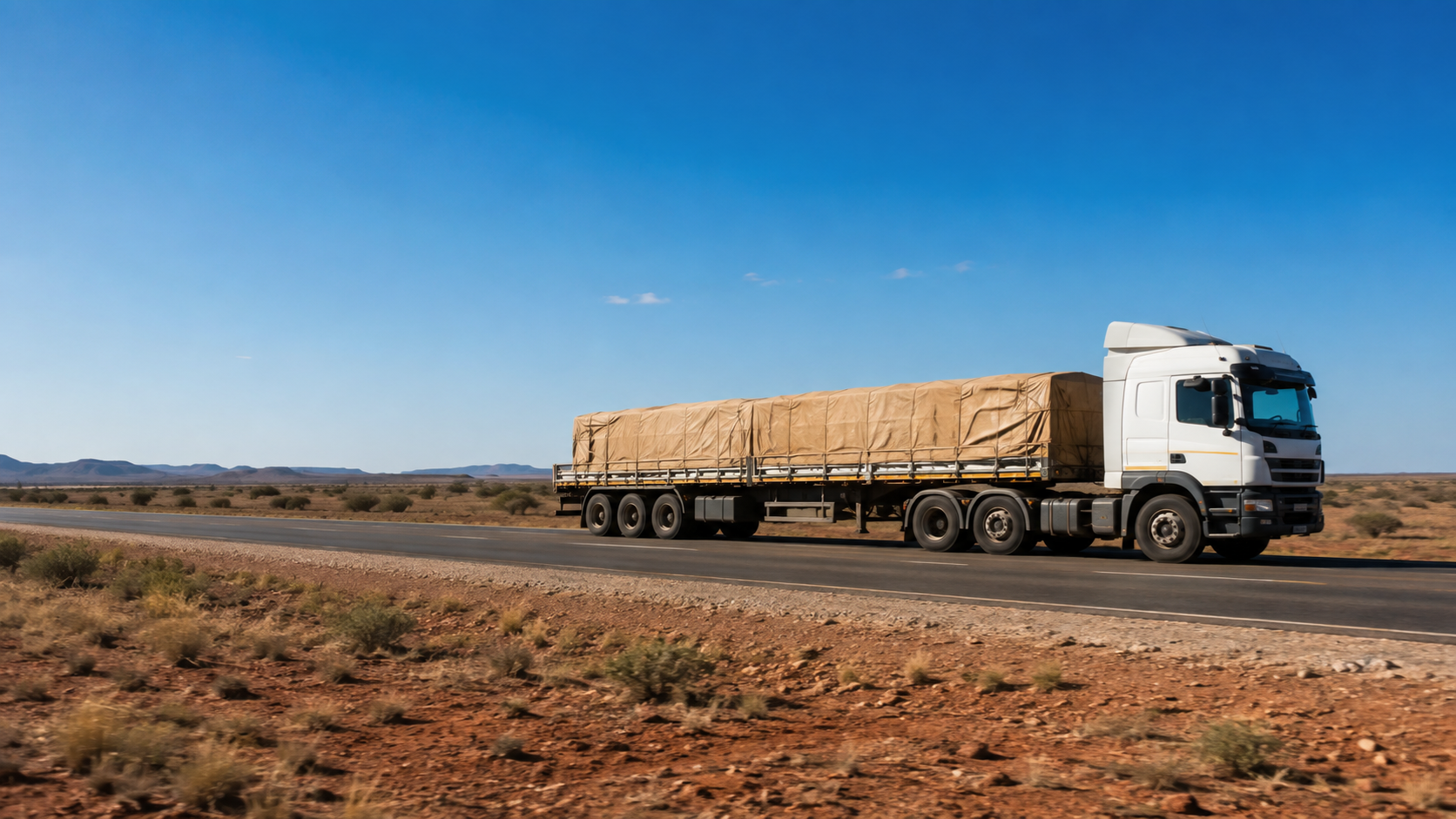 Loaded freight truck moving along an open highway under clear skies